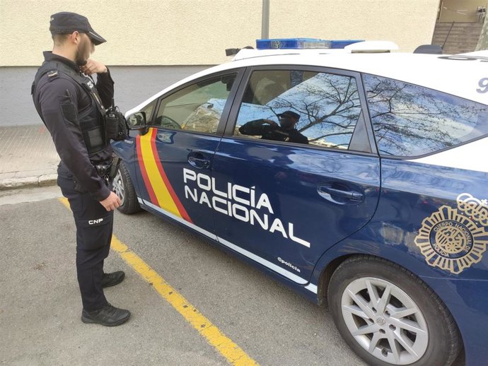 Un agente de la Policía Nacional, junto a un vehículo policial.