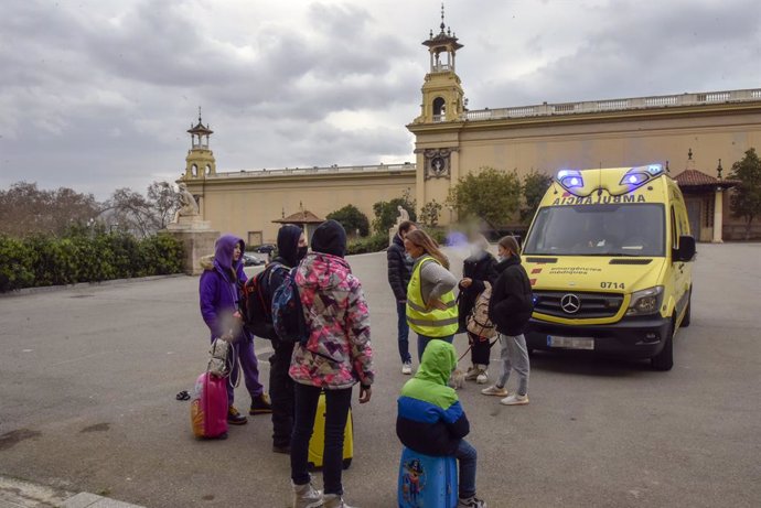 Varios refugiados y una traductora, junto a una ambulancia, en la entrada del palacio de Victoria Eugenia, el palacio 7 de Fira de Barcelona, convertido en un centro de recepción y atención de refugiados de Ucrania, a 18 de marzo de 2022, en Barcelona, 