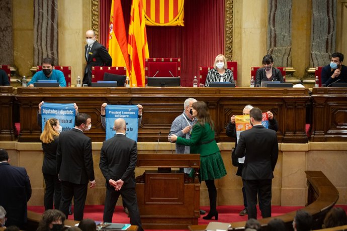 Activistas protestan en el pleno del Parlament con carteles críticos con los diputados