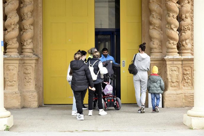 Varias personas refugiadas entran en el palacio de Victoria Eugenia, el palacio 7 de Fira de Barcelona, convertido en un centro de recepción y atención de refugiados de Ucrania, a 18 de marzo de 2022, en Barcelona