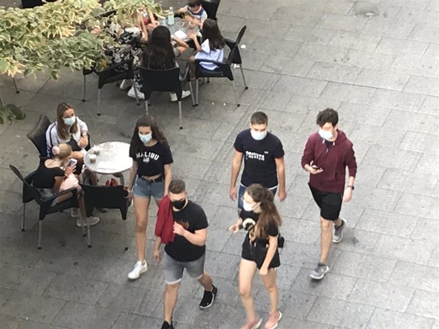 Archivo - Gente paseando con mascarilla delante de una terraza