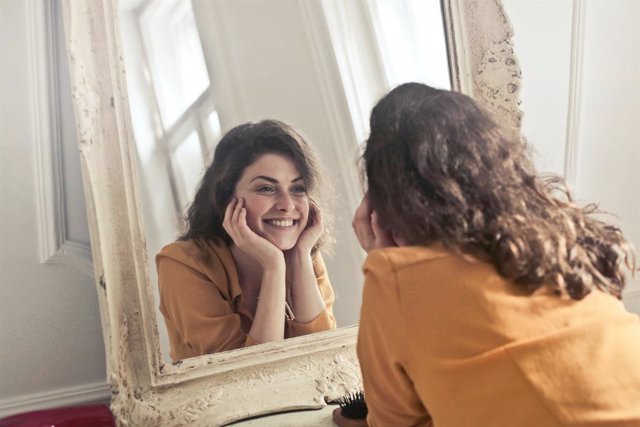 Una mujer mirándose en un espejo.