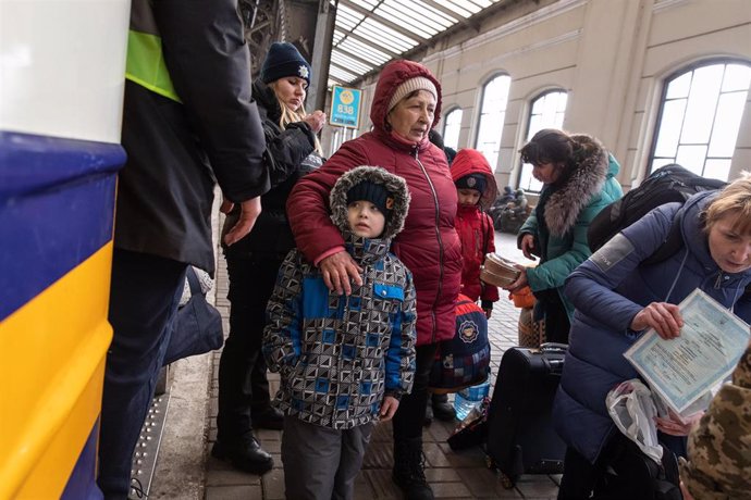 Varias familias esperando en Ucrania a que se comprueben sus pasaportes antes de subir al tren hacia Polonia. 