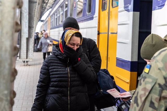 Una mujer llora mientras los soldados ucranianos comprueban su pasaporte antes de subir al tren hacia Polonia.