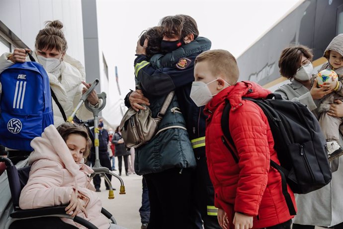 Un bombero abraza a una refugiada a su llegada, con niños, al Hospital Isabel Zendal, a 16 de marzo de 2022, en Madrid (España). Este grupo de personas ucranianas ha llegado a España gracias al convoy humanitario de la Fundación de La Asociación de Futb