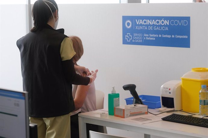 Archivo - Un sanitario vacuna a una persona contra la Covid-19 en Santiago.