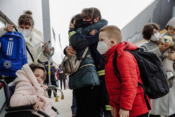 Un bombero abraza a una refugiada a su llegada, con niños, al Hospital Isabel Zendal, a 16 de marzo de 2022