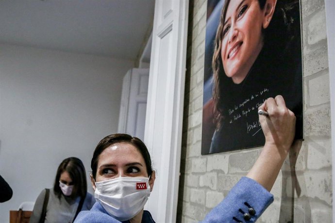 La presidenta de la Comunidad de Madrid, Isabel Díaz Ayuso,  firma una fotografía suya en la sede del PP en Chamberí. Archivo.
