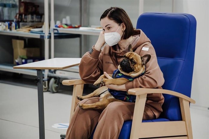 Una mujer refugiada, con un perro, espera a ser atendida, a su llegada al Hospital Isabel Zendal