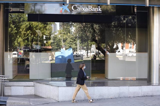 Archivo - Una mujer pasa por al lado de las oficinas de Caixabank en el Paseo Castellana, en Madrid (España) a 4 de septiembre de 2020. 