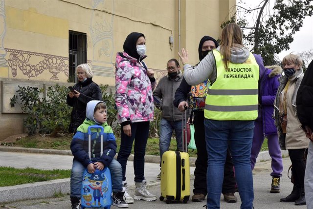 Varias personas refugiadas hablan con una traductora frente al palacio de Victoria Eugenia.