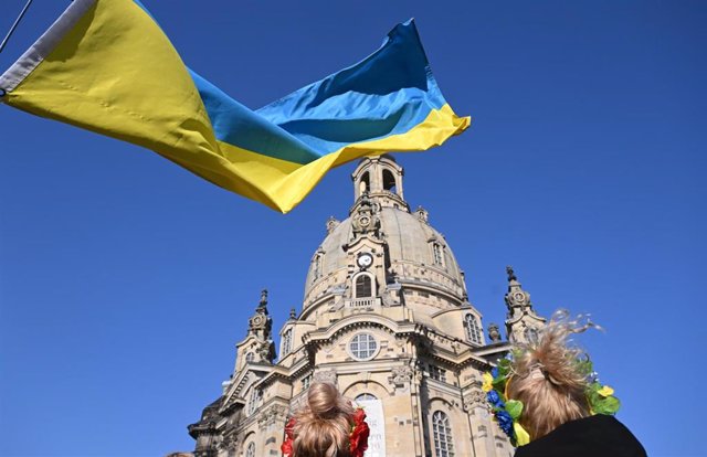 20 March 2022, Saxony, Dresden: Refugees from Kiev stand with a flag during a solidarity rally against the war in Ukraine on the New market in front of the Frauenkirche. Photo: Robert Michael/dpa-Zentralbild/dpa