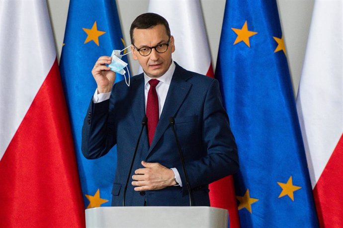 Archivo - El primer ministro de Polonia, Mateusz Morawiecki, se quita la mascarilla antes de un discurso