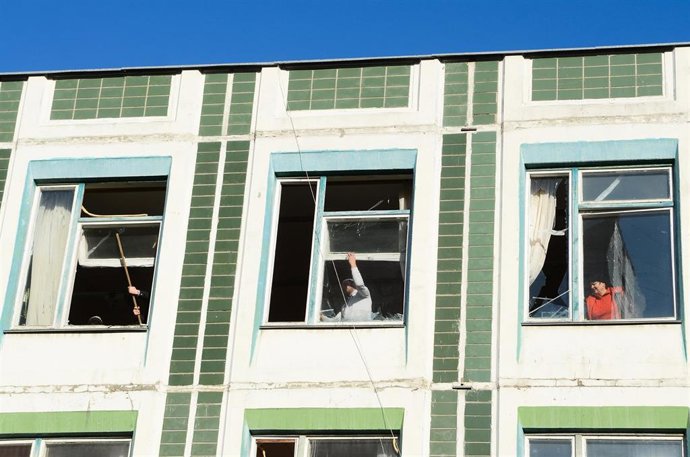 20 March 2022, Ukraine, Kiev: People remove glass shards from the windows of a school in the aftermath of shelling by Russian troops at a residential area of Kiev's Sviatoshynskyi district. Photo: -/Ukrinform/dpa