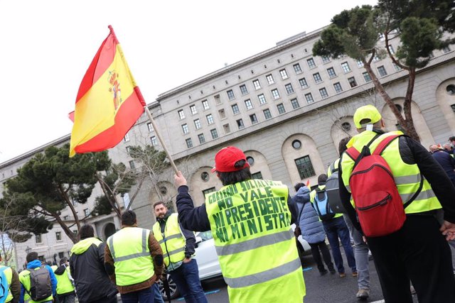 Una persona ondea una bandera de España durante una manifestación por el sector del transporte, en el Ministerio de Transportes, a 25 de marzo de 2022, en Madrid