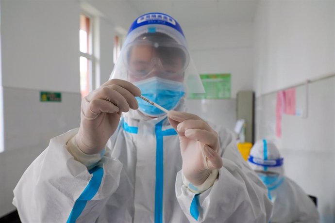 24 March 2022, China, Tengzhou: A health worker holds a thermometer at the experimental primary school in Tengzhou City. China reports 1,301 new locally transmitted cases of COVID-19. Photo: Song Haicun/SIPA Asia via ZUMA Press Wire/dpa