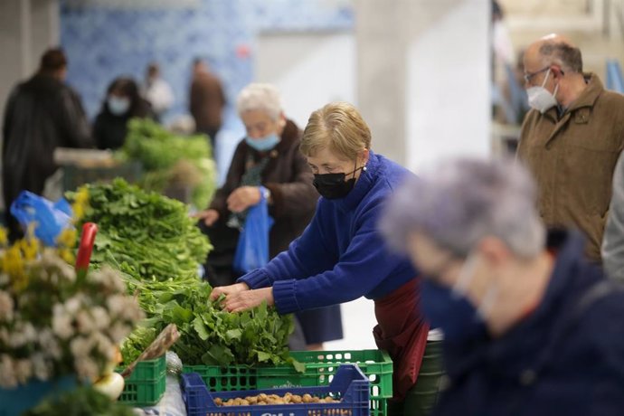 Varias personas en un puesto local de verduras y productos del campo, en el mercado tradicional de la Plaza de Abastos de Lugo, a 22 de marzo de 2022, en Lugo, Galicia (España). 