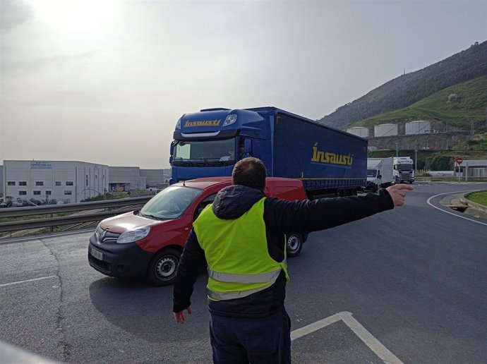 Un piquete informativo señaliza con la mano para tratar de impedir la entrada de un camión al Puerto de Bilbao.