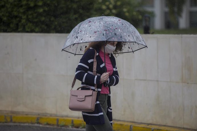 Archivo - Una mujer con paraguas y mascarilla en una imagen de archivo