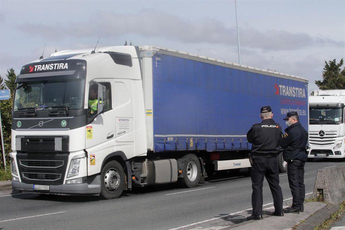 Dos agentes de Policía Nacional observan los camiones parados en el arcén en uno de los accesos al Polígono de O CEAO, en una huelga indefinida del transporte de mercancías, a 14 de marzo de 2022, en Lugo, Pontevedra (España). El paro, convocado a nivel