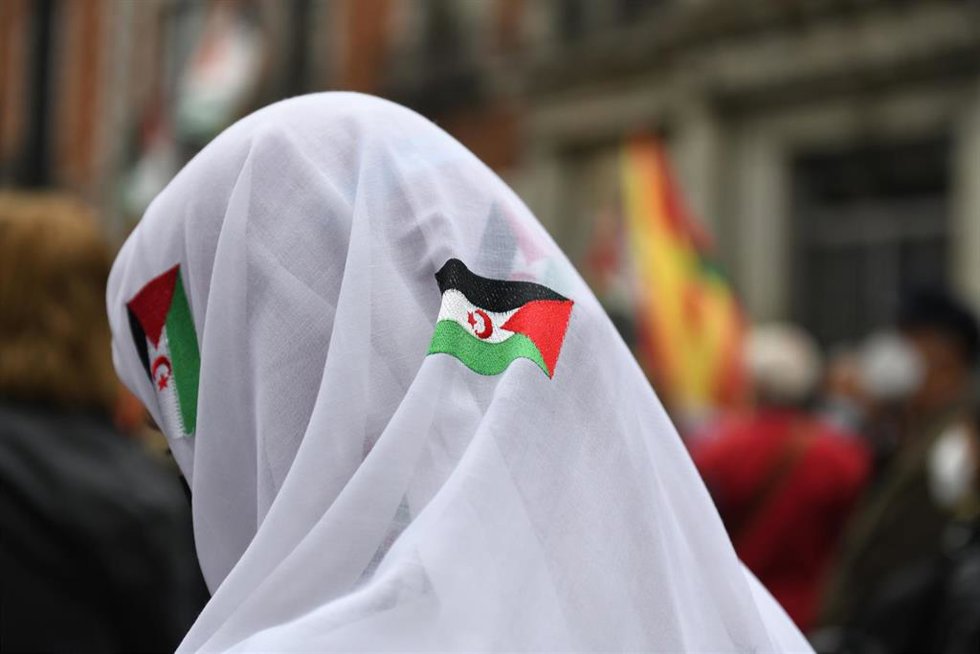 Una manifestante con un pañuelo blanco, con banderas sarahuis, en una manifestación convocada por la Coordinadora Estatal de Asociaciones Solidarias con el Sáhara (CEAS-Sáhara), frente al Ministerio de Asuntos Exteriores, a 26 de marzo de 2022