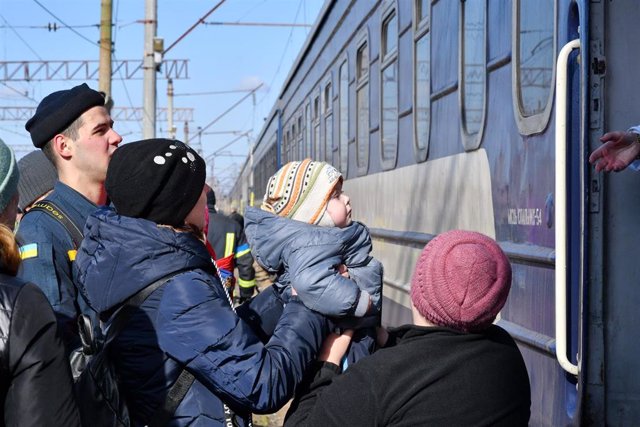 Una mujer ayuda a un niño a subirse a un tren en Ucrania.