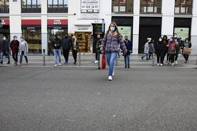 Archivo - Varias personas con bolsas pasean en una calle comercial del centro de Madrid