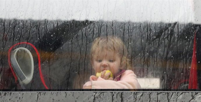 Un niño mira por una ventana, a su llegada a Madrid, tras haber finalizado un viaje en autobús fletado por REMAR RUMANÍA para escapar de Ucrania.