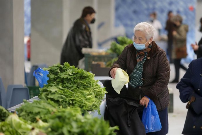 Una mujer compra verduras en un puesto local en una imagen de archivo.