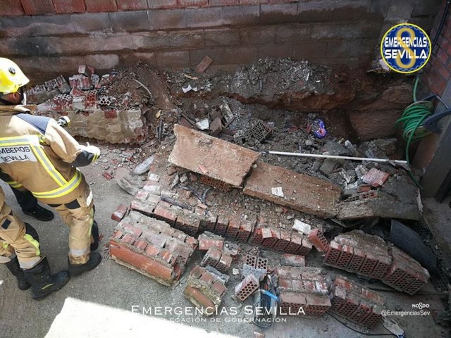 Bomberos asisten a un hombre tras quedar sepultado bajo un muro de una vivienda.