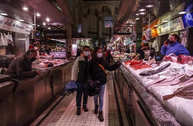Dos personas pasan por un puesto de pescado en el Mercado Central de Valencia, a 24 de marzo de 2022