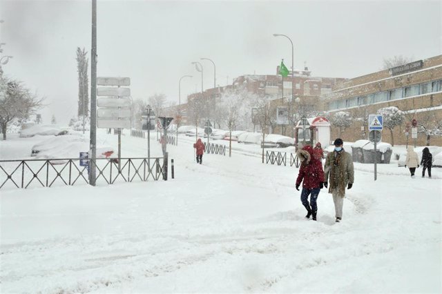 Archivo - Algunas personas caminan por una calzada completamente cubierta de nieve de una calle en Alcobendas, Madrid (España) a 9 de enero de 2021.