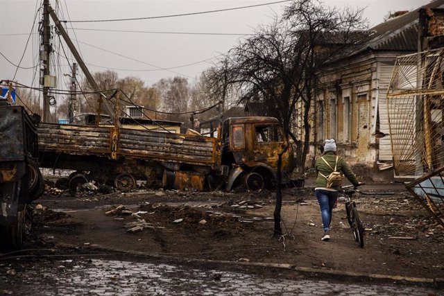 April 2, 2022, Trostyanets, Sumy, Ukraine: A woman walks her bike around destroyed Russian vehicles at Trostyanets, Ukraine on April 2, 2022. Russian troops held the city but have since been pushed back by Ukrainian forces.,Image: 676669337, License: Righ