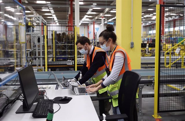 Dos trabajadores con ordenadores, en las instalaciones del Centro Logístico de Amazon, a 1 de abril de 2022, en Alcalá de Henares, Madrid (España).