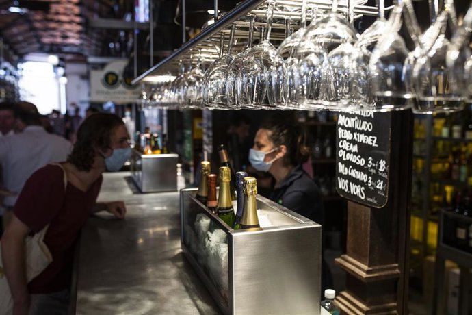 Archivo - Una persona conversa con una camarera durante la reapertura del Mercado de San Miguel, a 2 de julio de 2021, en Madrid, (España). Tras casi nueve meses de cierre temporal por la pandemia del coronavirus, el Mercado de San Miguel reabre hoy sus