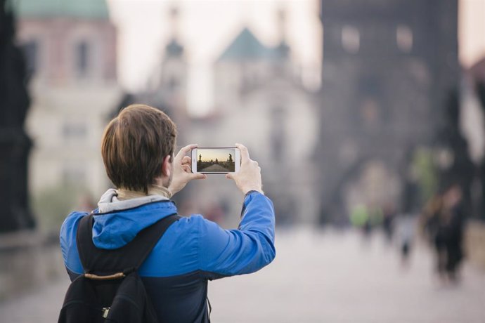 Archivo - Una turista fotografía el Puente de Carlos en Praga con su smartphone