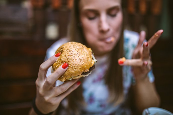 Archivo - Mujer disfrutando de una hamburguesa. 