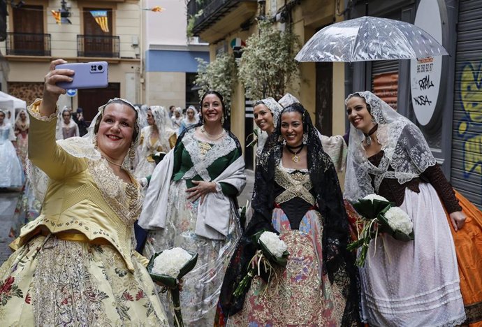 Varias falleras se hacen una fotografía durante la ofrenda floral a la Virgen de los Desamparados, a 17 de marzo de 2022, en Valencia, Comunidad Valenciana (España). La Junta Central Fallera ha decidido celebrar el desfile de esta tarde, pese al tempora