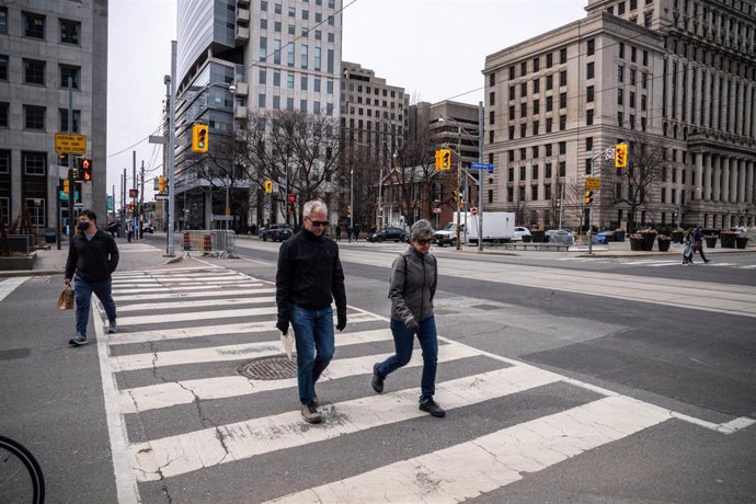 22 March 2022, Canada, Toronto: Pedestrians cross a street in Toronto. Mask mandate against COVID-19 has been lifted in Canadian Province Ontario after almost a year and a half. Photo: Katherine Cheng/SOPA Images via ZUMA Press Wire/dpa