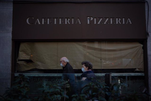Archivo - Dos ancianos con mascarilla en las inmediaciones de una Cafetería Pizzería de Barcelona en una imagen de archivo.