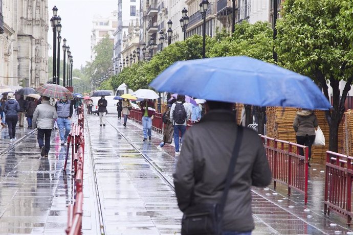 Varias personas por con sus parágüas en parte del trayecto de la Carrera Oficial durante la vuelta de la lluvia a Sevilla en plenos montaje de los palcos para la Semana Santa, a 5 de abril de 2022 en Sevilla (Andalucía, España)