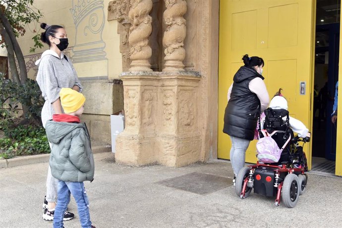 Dos mujeres y dos niños refugiados, uno en silla de ruedas, en la entrada del palacio de Victoria Eugenia, el palacio 7 de Fira de Barcelona, convertido en un centro de recepción y atención de refugiados de Ucrania