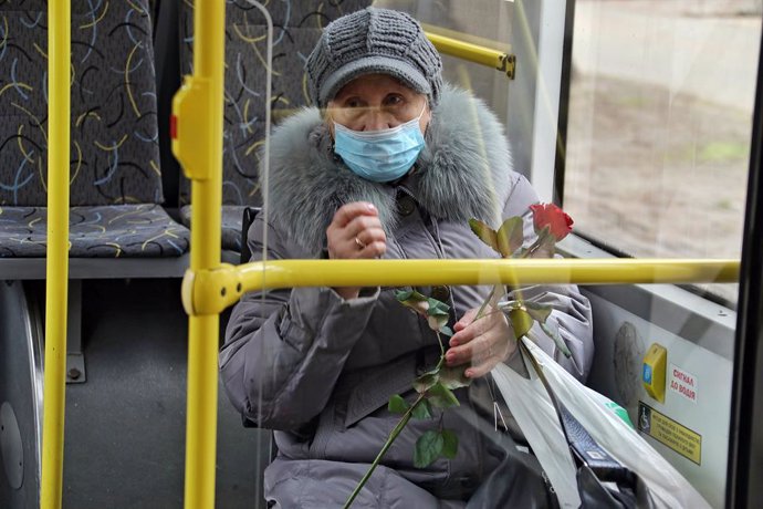 08 March 2022, Ukraine, Odessa: An elderly woman wearing a face mask holds a rose presented to her as part of a traditional International Women's Day activity in which women from Odessa receive flowers and free rides on a festively decorated bus. Photo: