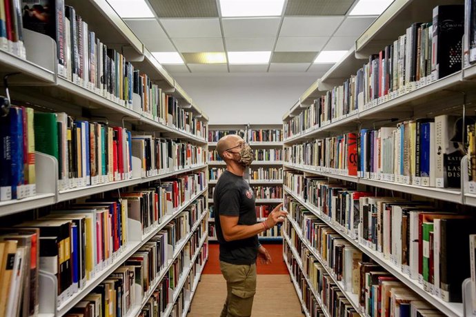 Archivo - Un hombre observa los libros de la biblioteca pública Elena Fortún, el primer día de fin de las restricciones de aforo en Madrid, a 4 de octubre de 2021, en Madrid (España). Los aforos se eliminan en los sectores de la actividad económica o so