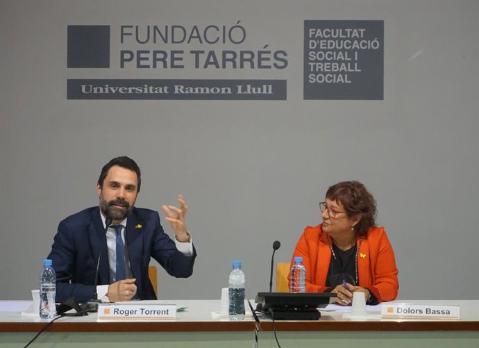 El Conseller d'Empresa i Treball, Roger Torrent, al costat de l'exconsellera Dolors Bassa durant la seva Intervenció