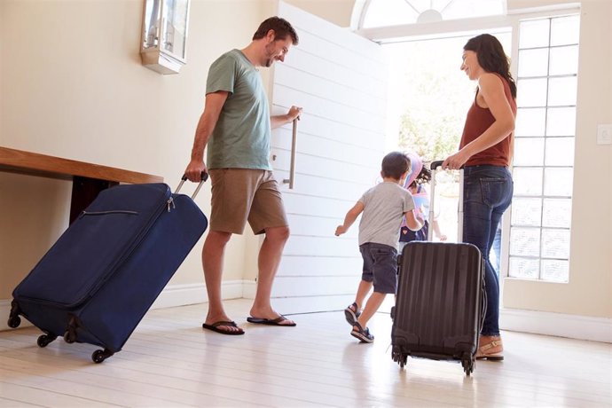Archivo - Una familia saliendo de su casa con maletas para iniciar sus vacaciones.