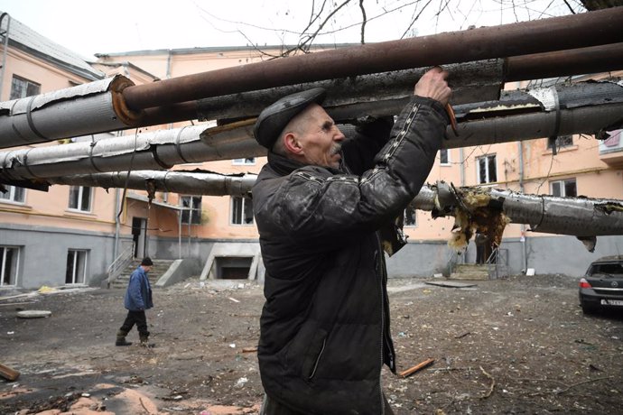 Archivo - Un home repara unes canonades després d'un bombardeig a l'autoproclamada República Popular de Donetsk.
