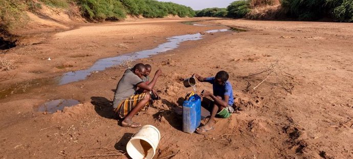 Un hombre y su hijo colectan agua del río Dollow, casi seco por la falta de lluvias, en Somalia