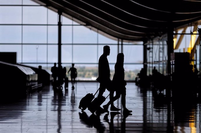 Archivo - Dos personas con equipaje, durante el día en el que se pone en marcha el certificado COVID Digital para garantizar la movilidad segura ante la COVID19, en la T4 del aeropuerto Adolfo Suárez, Madrid-Barajas, a 1 de julio de 2021, en Madrid (Esp