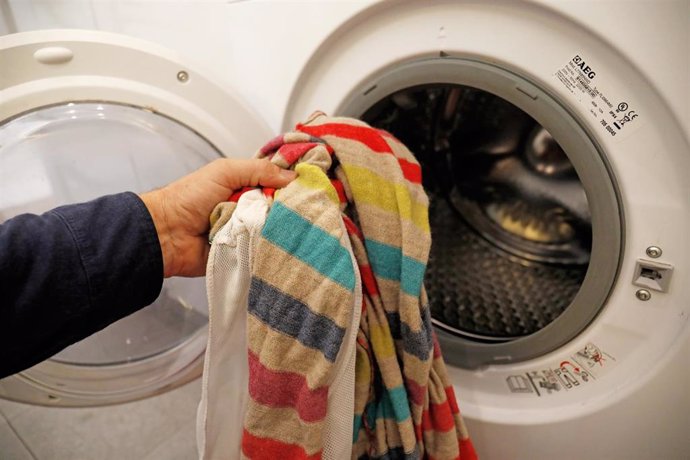 Archivo - Una persona introduce ropa sucia en una lavadora. 